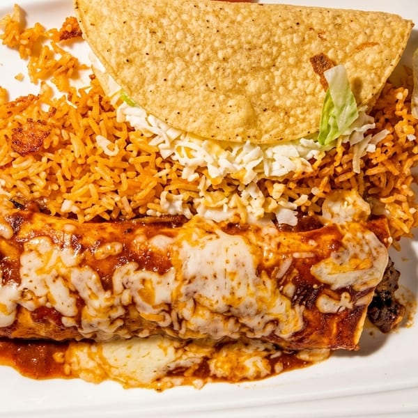 A cheesy enchilada, rice, and a taco with lettuce and cheese on a white plate.